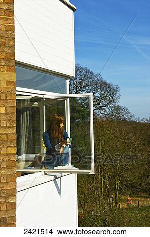 A young woman sits on a window ledge looking out, Hamstead Heath; London, England View Large Photo Image Picture - A young woman sits on a window ledge looking out, Hamstead Heath; London, England. Fotosearch