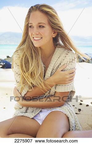 Stock Photo - A young woman sits on the beach of an hawaiian island; Maui, Hawaii, United States of America. Fotosearch