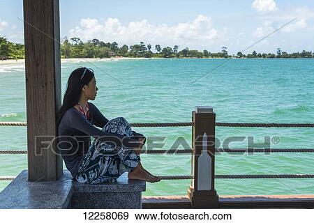 A young woman sits on the pier at Independence Beach; Sihanoukville, Cambodia View Large Photo Image Stock Photo - A young woman sits on the pier at Independence Beach; Sihanoukville, Cambodia. Fotosearch