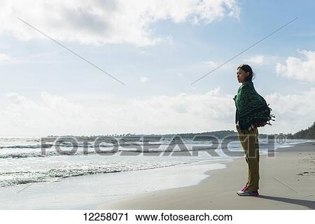 Stock Image - A young woman stands on Otres Beach looking out at the Gulf of Thailand; Sihanoukville, Cambodia. Fotosearch