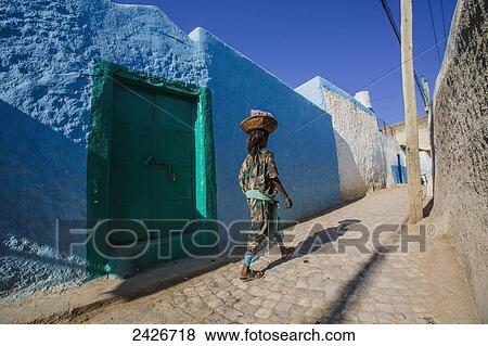 Stock Photo - A young woman walking through the colourful streets of the old City of Harar in Eastern Ethiopia; Harar, Ethiopia. Fotosearch