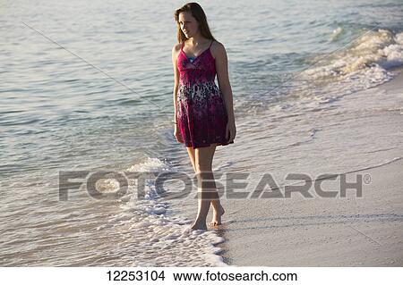 A young woman walks on the beach at the water's edge; Nokomis, Florida, United States of America View Large Photo Image Picture - A young woman walks on the beach at the water's edge; Nokomis, Florida, United States of America. Fotosearch