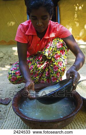 Stock Image - A young woman washes a bowl; Ulpotha, Embogama, Sri Lanka. Fotosearch
