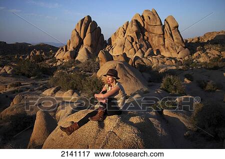 Stock Photo - A young woman watches the sunset in Joshua Tree National Park; California, United States of America. Fotosearch