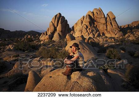 A young woman watches the sunset in Joshua Tree National Park; California, United States of America View Large Photo Image Stock Photo - A young woman watches the sunset in Joshua Tree National Park; California, United States of America. Fotosearch