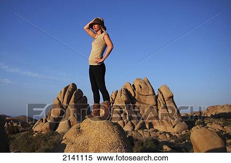 Stock Photography - A young woman watches the sunset in Joshua Tree National Park; California, United States of America. Fotosearch