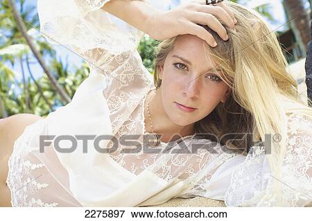 A young woman with long blond hair and a white sheer top posing on a beach; Maui, Hawaii, United States of America View Large Photo Image Stock Photo - A young woman with long blond hair and a white sheer top posing on a beach; Maui, Hawaii, United States of America. Fotosearch