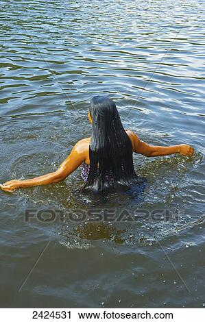 Stock Image - A young woman with long hair swims outside; Ulpotha, Embogama, Sri Lanka. Fotosearch