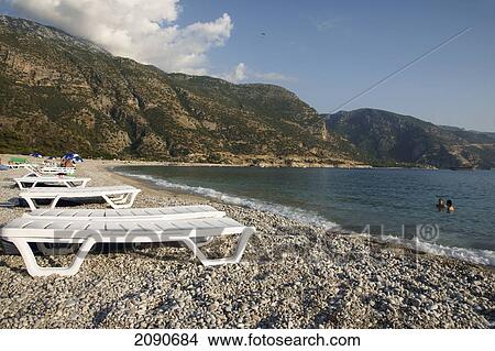 Abandoned Sun Loungers On A Pebbly Beach, The National Park, Oludeniz At The Turquoise Coast, Southern Turkey View Large Photo Image Picture - Abandoned Sun Loungers On A Pebbly Beach, The National Park, Oludeniz At The Turquoise Coast, Southern Turkey. Fotosearch