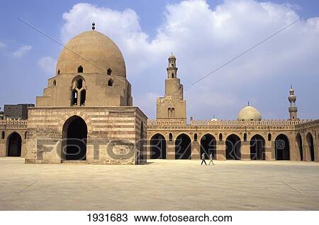 Stock Image - Ablutions Block, Minaret And Courtyard Of Ibn Tulun Mosque With Background People, Cairo, Egypt; Cairo, Egypt. Fotosearch