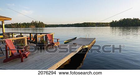 Adirondack Chairs On A Wooden Chair; Lake Of The Woods Ontario Canada View Large Photo Image Picture - Adirondack Chairs On A Wooden Chair; Lake Of The Woods Ontario Canada. Fotosearch