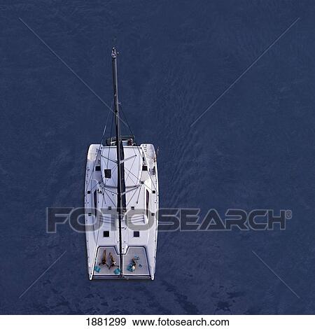 Stock Photo - Aerial View Of A Catamaran With Three Women Sunbathing; Belize. Fotosearch