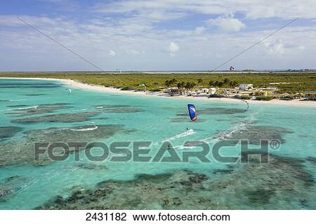 Stock Image - Aerial view of kiteboarders riding across the crystal clear blue waters; Anegada Island, British Virgin Islands. Fotosearch