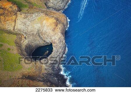 Stock Image - Aerial view of the rugged coastline and tide pool in a hole along an hawaiian island; Na Pali coast of Kauai, Hawaii, United States of America. Fotosearch