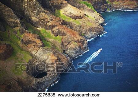 Aerial view of the rugged coastline and a boat in the pacific ocean along an hawaiian island; Na Pali coast of Kauai, Hawaii, United States of America View Large Photo Image Stock Photo - Aerial view of the rugged coastline and a boat in the pacific ocean along an hawaiian island; Na Pali coast of Kauai, Hawaii, United States of America. Fotosearch