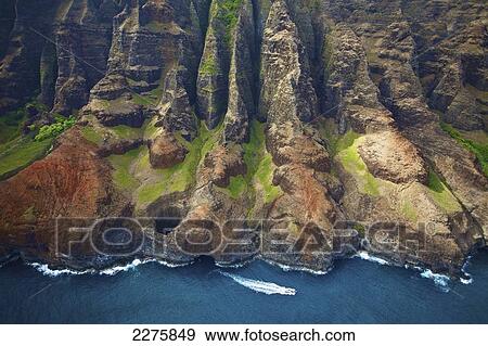 Aerial view of the rugged coastline and a boat in the pacific ocean along an hawaiian island, Na Pali coast; Kauai, Hawaii, United States of America View Large Photo Image Stock Photo - Aerial view of the rugged coastline and a boat in the pacific ocean along an hawaiian island, Na Pali coast; Kauai, Hawaii, United States of America. Fotosearch