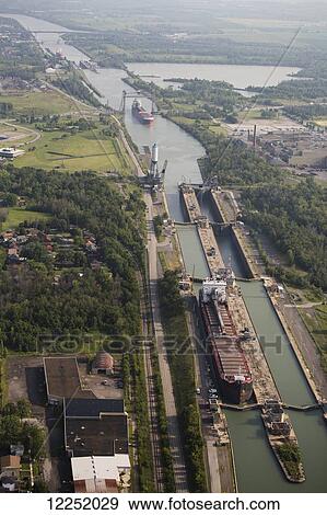 Stock Photo - Aerial view of the Welland Canal and a ship in a canal lock and another in the distance under a span bridge; Thorold, Ontario, Canada. Fotosearch