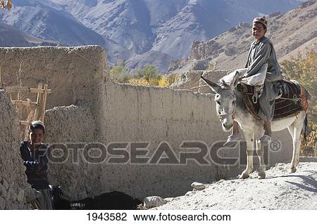 Stock Image - Afghan Boy On A Donkey Visiting Another Boy Near Shekh Ali, Parwan Province, Afghanistan. Fotosearch