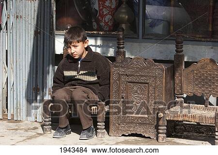 Picture - Afghan Boy Sitting On An Antique Chair In Chicken Street In Kabul,, Afghanistan. Fotosearch