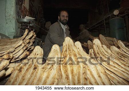 Stock Photography - Afghan Man And Freshly Baked Nan (Unleavened Bread) In A Kabul Bakery,, Afghanistan. Fotosearch