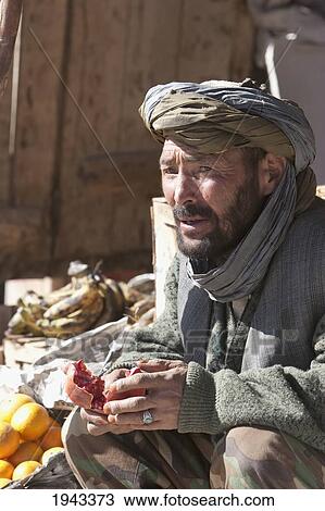 Afghan Man Enjoying A Pomegranate At The Bazaar In Bamiyan, Bamian Province, Afghanistan View Large Photo Image Stock Image - Afghan Man Enjoying A Pomegranate At The Bazaar In Bamiyan, Bamian Province, Afghanistan. Fotosearch