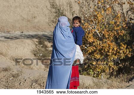 Stock Photography - Afghan Woman Wearing A Burqa Holding A Girl Along The Kabul-Charikar Road, Parwan Province, Afghanistan. Fotosearch