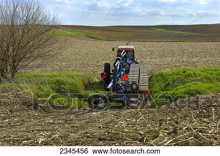 Stock Photograph - Agriculture - A Case IH tractor pulls a raised planter from a field just planted in no-till soybeans to another field to continue planting operations / Iowa, USA.. Fotosearch
