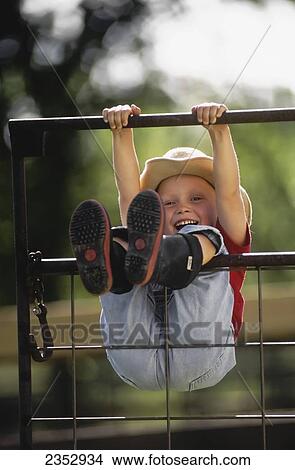 Agriculture - A young farm girl wearing a cowboy hat and rubber boots swings on a metal gate, hanging by her hands and legs and laughing / Northwest Missouri, USA. View Large Photo Image Picture - Agriculture - A young farm girl wearing a cowboy hat and rubber boots swings on a metal gate, hanging by her hands and legs and laughing / Northwest Missouri, USA.. Fotosearch