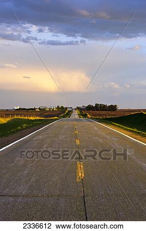 Stock Image - Agriculture - Crisp sunlight defines a rural country road and surrounding countryside after a spring storm has passed through / Central Iowa, USA.. Fotosearch