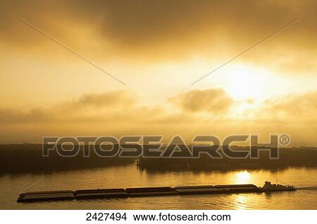 Picture - Agriculture - Grain barge navigating the Mississippi River in early morning light / near Hannibal, Missouri, USA.. Fotosearch