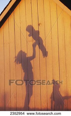 Agriculture - Silhouette on the side of a barn in late afternoon light of a farm woman, and mother, tossing her young child into the air while their dog watches / Northwest Missouri, USA. View Large Photo Image Picture - Agriculture - Silhouette on the side of a barn in late afternoon light of a farm woman, and mother, tossing her young child into the air while their dog watches / Northwest Missouri, USA.. Fotosearch