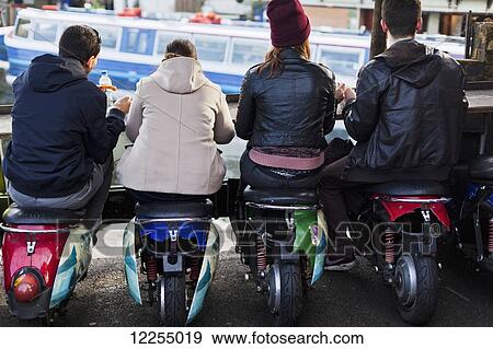 Stock Photo - Al fresco dining seated on motor scooter stools, Camden Market; London, England. Fotosearch
