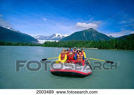 Stock Photo - Alaska, Front View Of Group Of People In Boat Rafting, Flat Water, Blue Sky, Mountains In Background. Fotosearch
