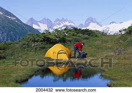 Stock Image - Alaska, Inside Passage, Man Sets Up Camp At Herbert Glacier And Snow Towers (Mountains). Fotosearch