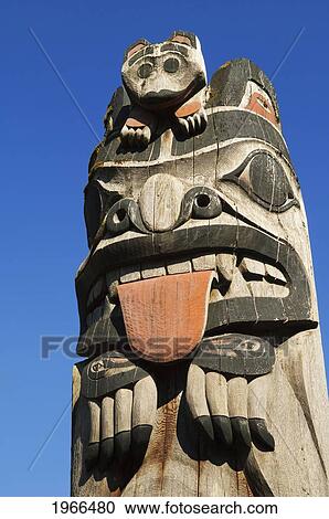 Stock Image - Alaska, Ketchikan, Cape Fox Lodge, Totem pole and blue sky.. Fotosearch