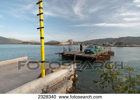 Stock Image - Albania, Man with his car on barge; Berint. Fotosearch