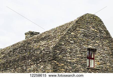 Stock Photography - All stone building (bee hive structure) with small red framed window; Dingle, County Kerry, Ireland. Fotosearch