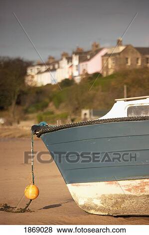 Stock Photo - Alnmouth, Northumberland, England; A Boat Sitting On The Shore With Houses In The Background. Fotosearch