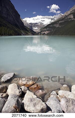 Stock Image - Alpine Lakeshore With Glacier Capped Mountains In The Background, Lake Louise, Banff National Park, Alberta. Fotosearch