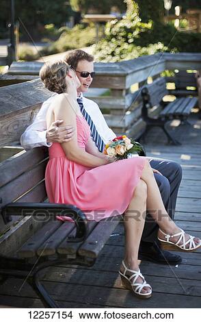 An affectionate couple sitting on a bench; Vancouver, British Columbia, Canada View Large Photo Image Picture - An affectionate couple sitting on a bench; Vancouver, British Columbia, Canada. Fotosearch