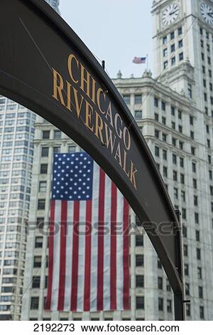 Stock Image - An American Flag Hands On The Side Of A Building With The Sign Of The Chicago Riverwalk; Chicago Illinois United States Of America. Fotosearch