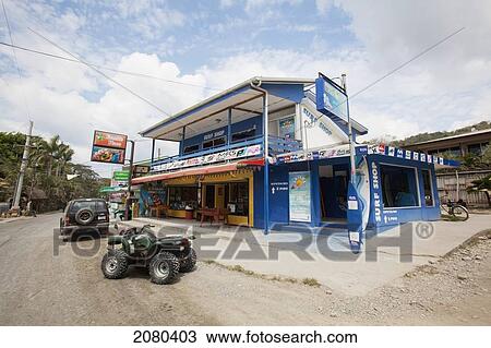 Stock Image - An Atv Sits On The Dusty Dirt Road In Front Of A Surf Shop In Santa Teresa And Mal Pais (Malpais) On The Nicoya Peninsula; Puntarenas Province, Costa Rica. Fotosearch