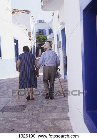 Stock Image - An Elderly Couple Wander Down The Street. Fotosearch