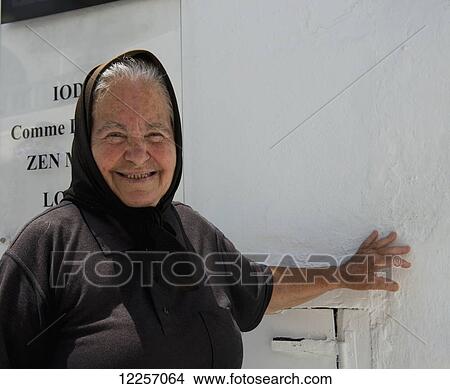 An elderly Greek lady dressed in black outside a designer boutique; Mykonos Town, Mykonos, Cyclades, Greek Islands, Greece View Large Photo Image Picture - An elderly Greek lady dressed in black outside a designer boutique; Mykonos Town, Mykonos, Cyclades, Greek Islands, Greece. Fotosearch