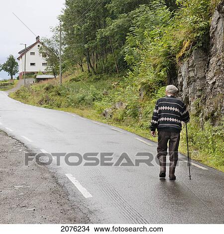 Picture - An Elderly Man Walks Up The Road; Hardangervidda Norway. Fotosearch