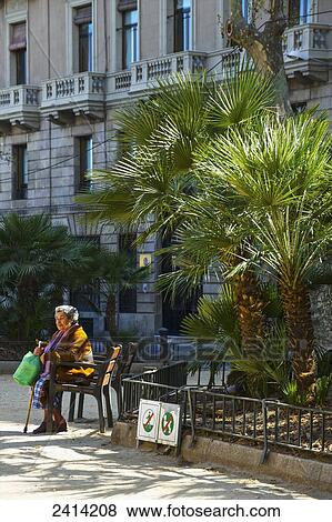 An elderly woman sits on a chair outside a residential building; Barcelona, Spain View Large Photo Image Stock Photo - An elderly woman sits on a chair outside a residential building; Barcelona, Spain. Fotosearch