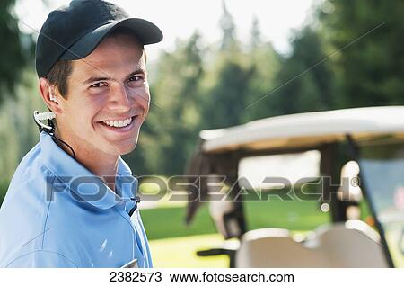 Stock Image - An enthusiastic male member of the guest services team at the Whistler Golf Course; Whistler, British Columbia, Canada. Fotosearch