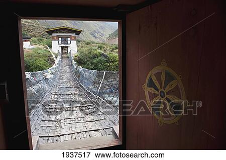 Stock Photo - An Iron Suspension Bridge At Tamchhog Lhakhang Monastery Over The Paro Chhu River; Bhutan. Fotosearch