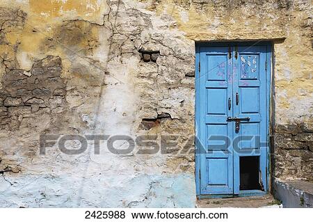 Stock Photo - An old, broken blue door along a cracked wall; Hampi, Karnataka, India. Fotosearch