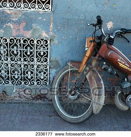 Stock Photo - An Old Motorcycle Parked By A Weathered Wall; Marrakesh, Marrakech-Tensift-El Haouz, Morocco. Fotosearch